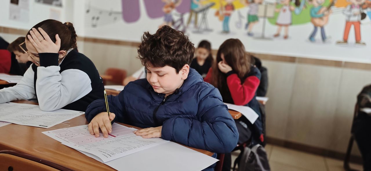A group of children taking a test with focus and concentration in a classroom setting.